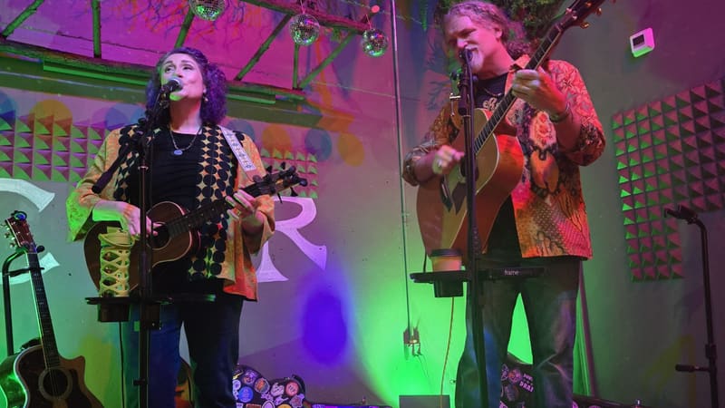 The duo playing under pink and green stage lights