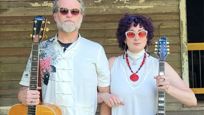 Kristi Casey and Steven Glude on a porch holding their guitars upright, facing the camera