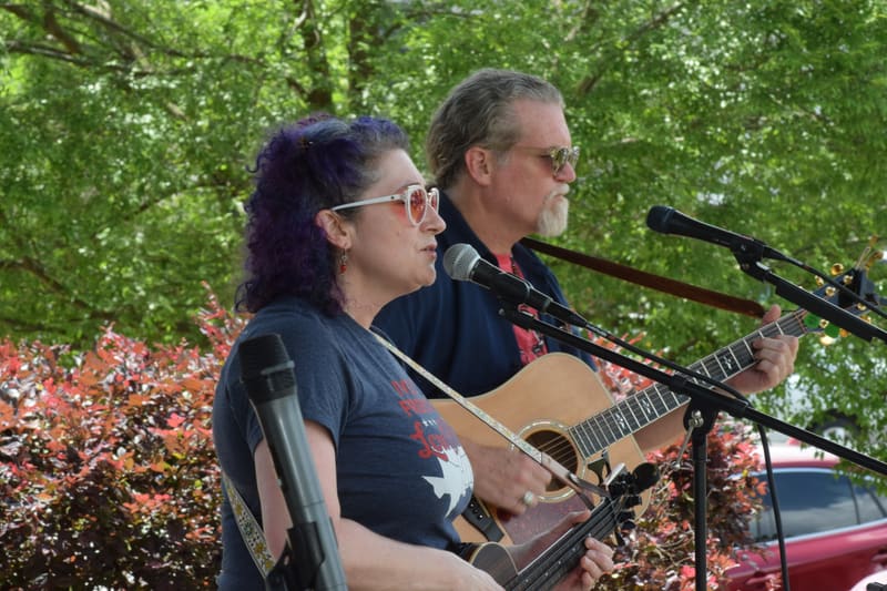 Kristi and Steven singing into two mics outdoors